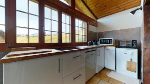 a large kitchen with white appliances and windows at Les Hirondelles, cosy apartment with a magnificent view on the mountains in La Forclaz