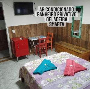 een slaapkamer met een bed en een tafel en een televisie bij Pousada Quintal Verde Floripa in Florianópolis