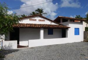 una casa blanca con una palmera delante en Casinha da Curva, en Icaraí