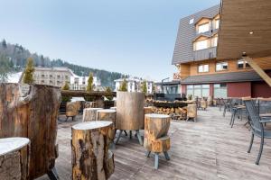 a patio with wooden logs and tables and chairs at Apartment B513 in Jahorina