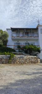 a white house with a stone wall in front of it at Skalopati Studios & Villa in Panormos Skopelos