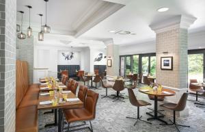 voco St. Johns Solihull, an IHG Hotel في سوليهال: مطعم بطاولات وكراسي ونوافذ