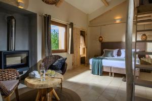 Country Hotel Velani في Avdou: غرفة نوم بسرير ومدفأة وتلفزيون