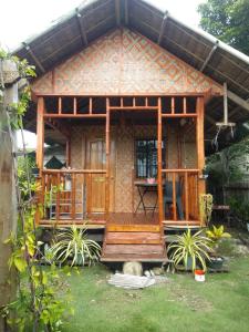 a small wooden house with a porch in a yard at Titanic's Nipa Hut in Moalboal