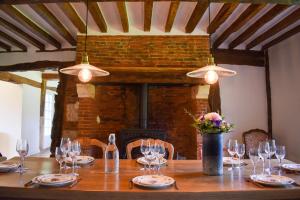 a wooden table with wine glasses and a fireplace at La Normande -Piscine- 10 min Pont Audemer 10P in Saint-Symphorien