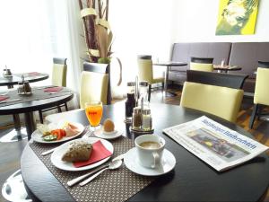 a table with plates of food and a newspaper at Best Western Plus Amedia Art Salzburg in Salzburg