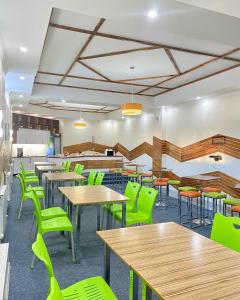 a cafeteria with wooden tables and green chairs at Caravan Hotel in Karakol