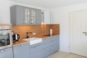 a kitchen with gray cabinets and a white sink at Tant Berta´s Huus in Krummhörn