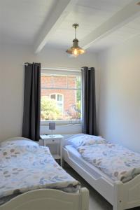 2 camas en una habitación con ventana en Tant Berta´s Huus, en Krummhörn