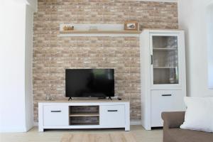a living room with a tv on a brick wall at Tant Berta´s Huus in Krummhörn
