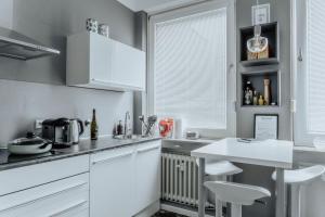 ミュンスターにあるStylisches Münster City-Apartment 83 m²の白いキャビネットとテーブルと椅子のあるキッチン
