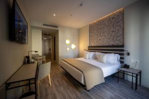 Una habitación de hotel con una cama, un escritorio y un televisor. en abba Sevilla, en Sevilla