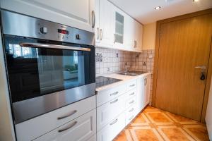 una cocina con armarios blancos y horno negro en Farm Stay Ana, en Višnja Gora
