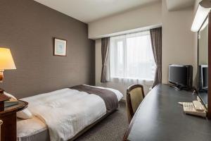 豊川市にあるコンフォートホテル豊川のベッド、デスク、テレビが備わるホテルルームです。