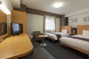ein Hotelzimmer mit 2 Betten und einem Flachbild-TV in der Unterkunft Comfort Hotel Narita in Narita