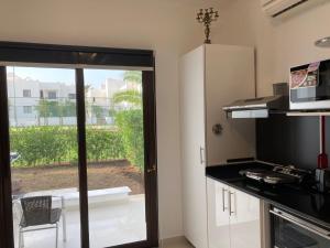 een keuken met een glazen schuifdeur naar een balkon bij Diar El Rabwa Modern Apartment with Free WiFi and Private Balcony in Sharm El Sheikh