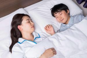 Comfort Hotel Gifu في غيفو: رجل وامرأة ينامان على سرير