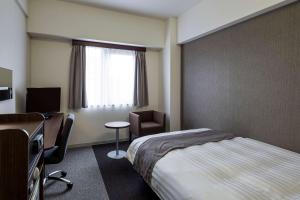 um quarto de hotel com uma cama, uma secretária e uma janela em Comfort Hotel Sakai em Sakai