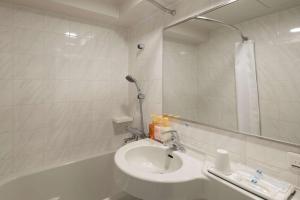 La salle de bains est pourvue d'un lavabo, d'une baignoire et d'un miroir. dans l'établissement Comfort Hotel Sakai, à Sakai