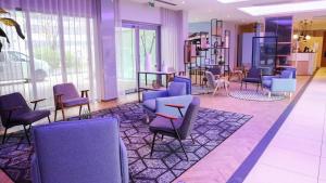 a waiting room with purple chairs and tables at Radisson Blu Hotel Toulouse Airport in Blagnac