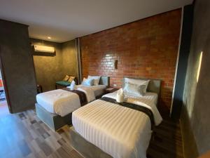 two beds in a room with a brick wall at Khum Lanna Boutique Hotel in Si Sa Ket