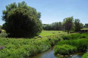 einen Fluss mit einem Zaun neben einem Feld in der Unterkunft The Bridge House; BW Signature Collection in Ferndown