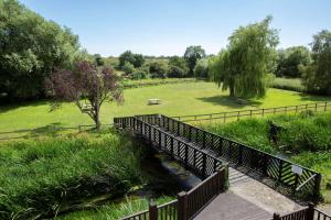 a wooden bridge over a river in a park at The Bridge House; BW Signature Collection in Ferndown