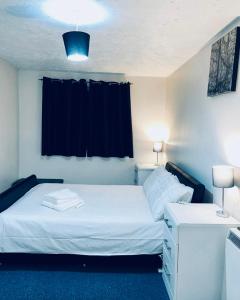 - une chambre avec un lit blanc et une fenêtre noire dans l'établissement Service Apartment, à Thamesmead