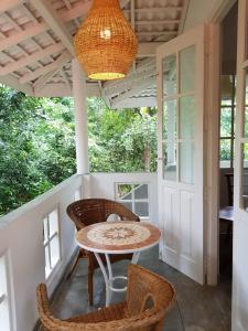 a porch with a table and chairs and a chandelier at JJ JungleJoy Villa in Unawatuna