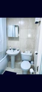 a bathroom with a white toilet and a sink at Service Apartment in Thamesmead