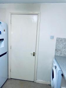 a white door in a kitchen with a washing machine at Service Apartment in Thamesmead