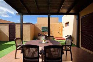 Un patio con una mesa y sillas en un porche. en Villa Dayely, en Corralejo