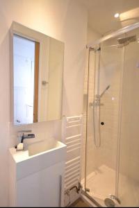 a white bathroom with a sink and a shower at Compact, central apartment, dog friendly. in Kingsbridge