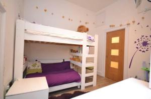 a bedroom with a bunk bed with purple sheets at Compact, central apartment, dog friendly. in Kingsbridge