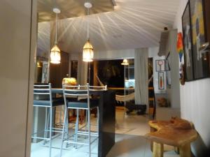 a living room with a table and stools in it at Bangalô no alto da colina no Villas do Pratagy - Maceió in Maceió