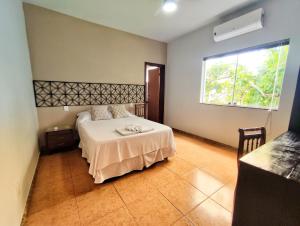 um quarto com uma cama com um cobertor branco e uma janela em Pousada Villa Magna - Chalé Família em Diamantina