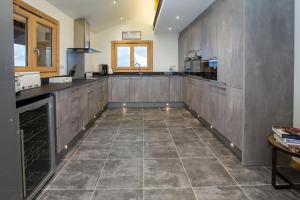 a large kitchen with gray cabinets and a tile floor at Chalet Lumina in Morzine