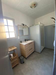 baño con lavabo, armario y ventana en Le cocon des Nestes, en Arreau