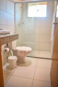 a bathroom with a toilet and a glass shower at Flat AGC in Morro de São Paulo