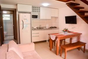 a small kitchen with a table and a refrigerator at Flat AGC in Morro de São Paulo