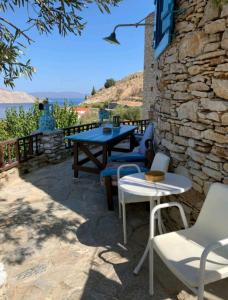 eine Terrasse mit einem Tisch, Stühlen und einer Steinmauer in der Unterkunft The Windmill in Symi