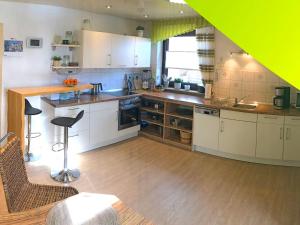 a kitchen with white cabinets and a wooden floor at Ferienwohnung Elisabeth in Burgbernheim +2 photos