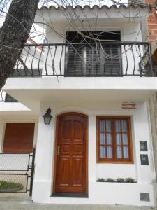 Casa blanca con puerta de madera y balcón en Locaciones Colon en Colón