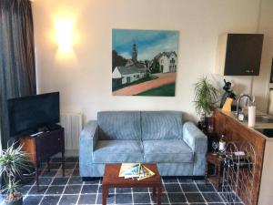 uma sala de estar com um sofá azul e uma televisão em B&B In de Oude Smederij Zaltbommel em Zaltbommel