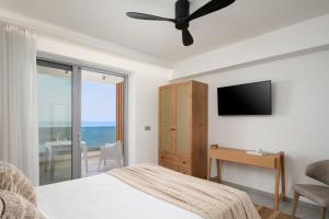 a bedroom with a bed and a television and a desk at Hermes Grand Luxury Beachfront Villa & Spa, By ThinkVilla in Skaleta +60 photos