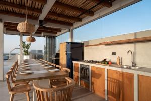a kitchen with a long wooden table and chairs at Hermes Grand Luxury Beachfront Villa & Spa, By ThinkVilla in Skaleta