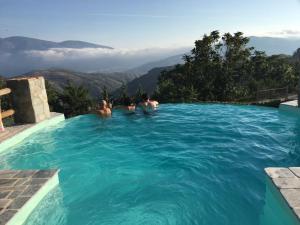 Tres personas en una piscina con montañas en el fondo en Cortijo Privilegio, en Lanjarón