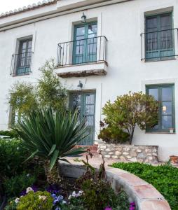 une maison blanche avec des fenêtres et des plantes devant elle dans l'établissement Cortijo Privilegio, à Lanjarón