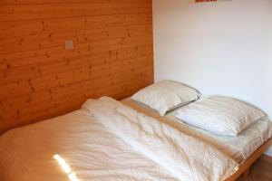 a bed in a bedroom with a wooden wall at Chalet Amos in Grimentz