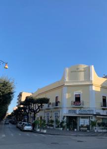 un grand bâtiment blanc sur le côté d'une rue dans l'établissement Hotel Apollo, à Pompéi